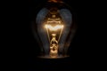 Close up of a vintage light bulb with glowing filament isolated on black background Royalty Free Stock Photo