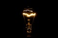 Close up of a vintage light bulb with glowing filament isolated on black background Royalty Free Stock Photo