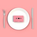 Close up of vintage pink audio tape cassette on plate, knife and fork on pink background, Top view with copy space