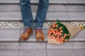 Close-up of vintage shoes with purple laces and a bouquet of ros