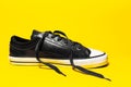 Close-up of vintage sneaker shoe with lace out on yellow background.