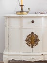 Close-up of vintage wooden bedside table with metal fitment. Candle and glasses for reading for cosy atmosphere.