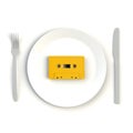 Close up of vintage yellow audio tape cassette on plate, knife and fork on white background, Top view with copy space Royalty Free Stock Photo