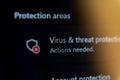 Close-up of virus and threat protection settings on a computer screen showing a red alert icon and actions needed Royalty Free Stock Photo