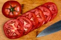 A Close up vivid image of tomato slices on a bamboo cutting board