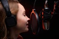 Close-up Vocalist working in the studio with a studio microphone in headphones. Against a dark background, with red smoke. Effect