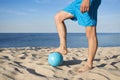 A close-up of volleyball and the mens feet on the beach. The concept of a healthy lifestyle