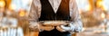 Close-up of a waiter holding an empty silver tray in a luxurious restaurant setting, ready to serve. Royalty Free Stock Photo