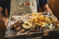 Close-up of a waiter serving delicious barbecued prime rib with french fries