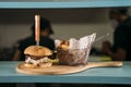 Close-up of a waiter using face mask serving a delicious meat burger with fries