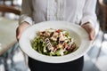 Close Up Of Waitress Holding Plate Of Chicken Salad In Restaurant