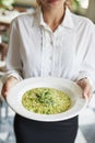 Close Up Of Waitress Holding Plate Of Pea And Mint Risotto In Restaurant