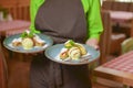 Close up of waitress serving apple strudel with vanilla ice cream and mint on blue plate. Restaurant or cafe service.