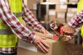 Close-up of warehouse workers preparing a shipment in a large warehouse, putting glue tape on boxes Royalty Free Stock Photo