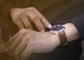 Close-up of watch on wrist of man. Men in black shirt looking at his luxury watches brown leather strap that are worn in the hands Royalty Free Stock Photo