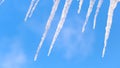 Close up of water dripping from icicles on blue sky background with floating clouds. Concept. Global warming and Royalty Free Stock Photo