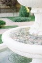 Close up on water dripping out of white stone fountain in beautiful spring flower garden. Shallow Depth of Field Royalty Free Stock Photo