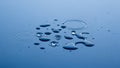 Close up of water droplets creating ripples on a smooth blue surface Royalty Free Stock Photo