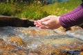 Close-up of water drops falling from female hands into a stream. The hand touches fresh water. A tourist drinks water Royalty Free Stock Photo