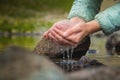 Close-up of water drops falling from female hands into a stream. The hand touches fresh water. A tourist drinks water Royalty Free Stock Photo