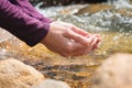Close-up of water drops falling from female hands into a stream. The hand touches fresh water. A tourist drinks water Royalty Free Stock Photo