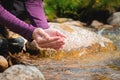 Close-up of water drops falling from female hands into a stream. The hand touches fresh water. A tourist drinks water Royalty Free Stock Photo