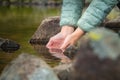 Close-up of water drops falling from female hands into a stream. The hand touches fresh water. A tourist drinks water Royalty Free Stock Photo