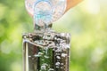 Close up of water flowing from drinking water bottle into glass on blurred green bokeh background Royalty Free Stock Photo