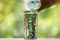 Close up of water flowing from drinking water bottle into glass on blurred green bokeh background Royalty Free Stock Photo