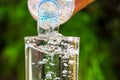 Close up of water flowing from drinking water bottle into glass on blurred green garden background Royalty Free Stock Photo