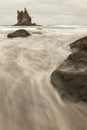 Close-up of water movement, rocks and landmark in background. Royalty Free Stock Photo