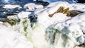 Close up of the water of the Murtle River tumbles over the edge of the partly frozen Mushbowl Falls in Wells Gray Provincial Park