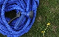 close up of watering hose lies on the grassy ground. blue rubber tube with device for spraying and watering plants in Royalty Free Stock Photo