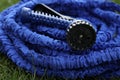 close up of watering hose lies on the grassy ground. blue rubber tube with device for spraying and watering plants in Royalty Free Stock Photo