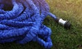 close up of watering hose lies on the grassy ground. blue rubber tube with device for spraying and watering plants in Royalty Free Stock Photo