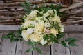 Close up of wedding bouquet of beige flowers and greenery on wood background, copy space.