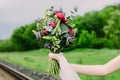 Close up of wedding bouquet with green, red and violet flowers and white ribbon. Bride with wedding bouquet in her hands. Royalty Free Stock Photo