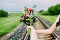 Close up of wedding bouquet with green, red and violet flowers and white ribbon. Bride with wedding bouquet in her hands. Royalty Free Stock Photo