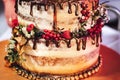 Close up of wedding cake with dripped chocolate and decorated with various berries. Sweet passion concept.