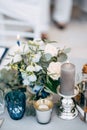 Close-up of a wedding dinner table at reception. A large thick gray candle stands in a silver glossy candlestick, next