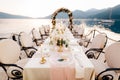 Close-up of a wedding dinner table reception. A table stands on beach overlooking mountains at sunset. Metal forged