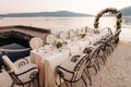 Close-up of a wedding dinner table reception. A table stands on beach overlooking mountains at sunset. Metal forged