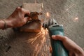 Close up of welder`s hand using a grinder to smooth the surface of the iron hinge