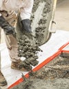 Wet cement off loaded by construction worker from a cement truck chute into a concrete form with rebar