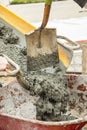 Close up of Wet cement off loaded by construction workers from a cement truck chute into a wheelbarrow