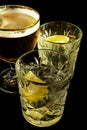 Close up of a wet glass of cold light beer with foam and vermouth Martini alcohol cocktail with yellow lemon slice and ice cubes o Royalty Free Stock Photo