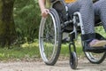 Close-up of a wheelchair from the front, a young woman sitting on it, in nature Royalty Free Stock Photo