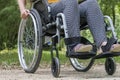 Close-up of a wheelchair from the front, a young woman sitting on it, in nature Royalty Free Stock Photo