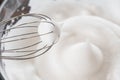 Close-up of a whisk and beaten egg whites to stiff peaks, a step in the preparation of breakfast dough or tender pancakes. White Royalty Free Stock Photo