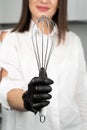 Close-up of a whisk in the hands of a pastry chef. Young female confectioner with whisk